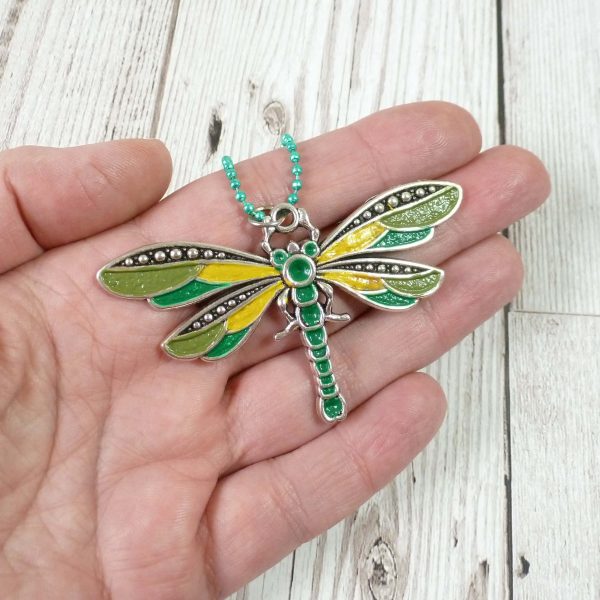 Green and yellow dragonfly pendant on hand