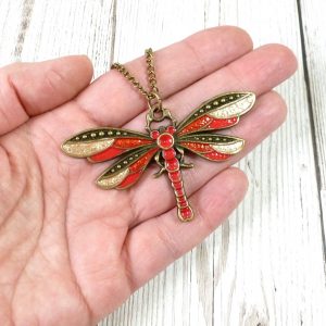Red, Brick and gold bronze dragonfly pendant on hand
