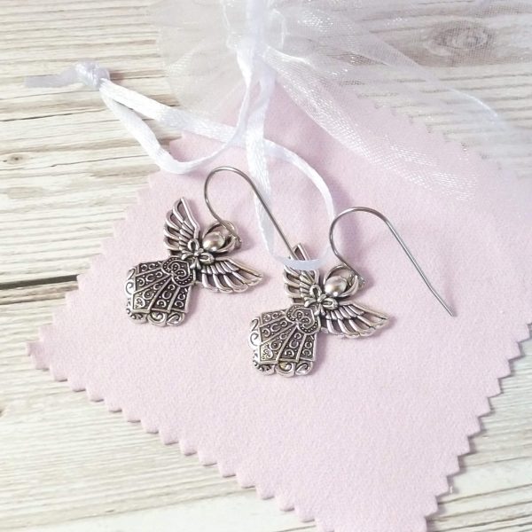 silver angel earrings on pink background