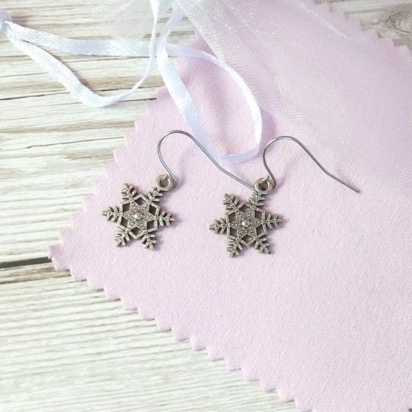 spikey snowflake earrings on pink background
