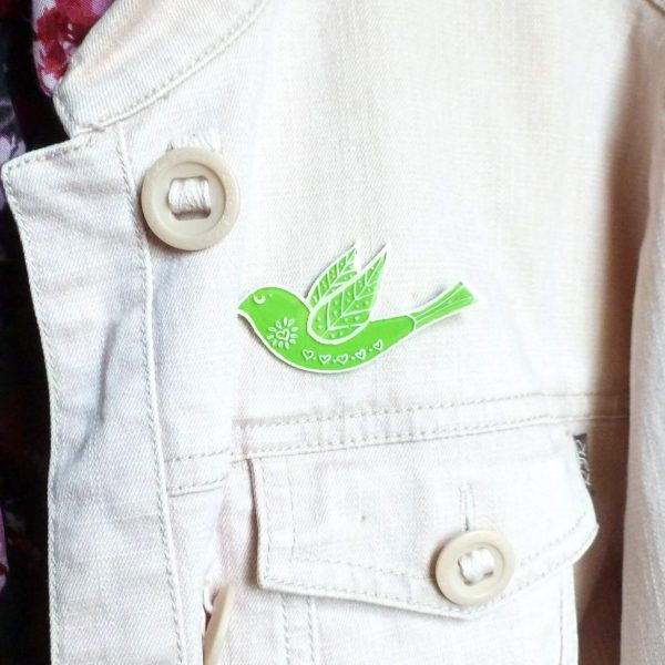 Lime green folk art style bird brooch on jacket
