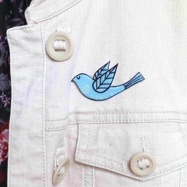 Pale blue folk art style bird brooch on jacket