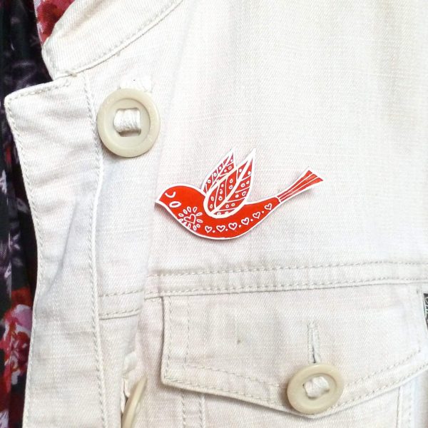 red folk art style bird brooch on jacket