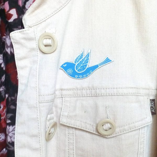 Blue folk art style bird brooch on jacket