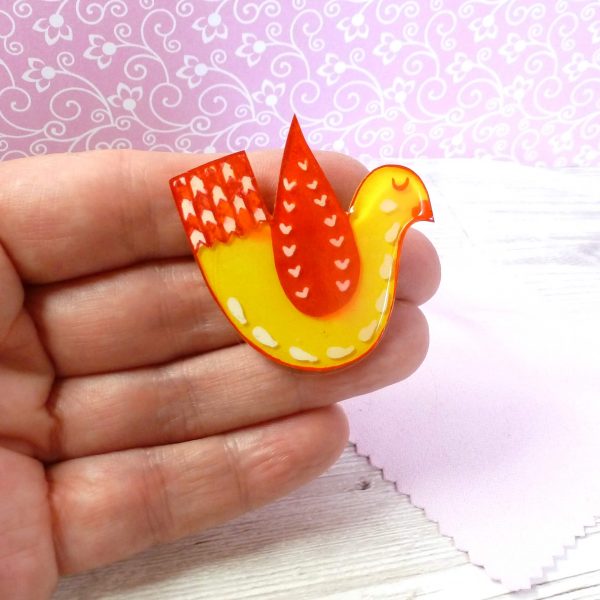 Yellow and red love bird brooch on hand