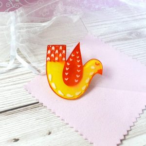 Yellow and red love bird brooch on background