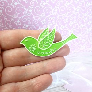 Lime green folk art style bird brooch on hand