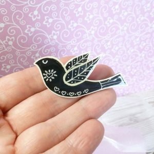 Black folk art style bird brooch on hand