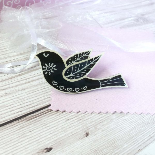 Black folk art style bird brooch on pink background