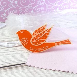 Orange folk art style bird brooch on pink background
