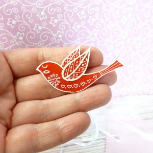 Red folk art style bird brooch on hand