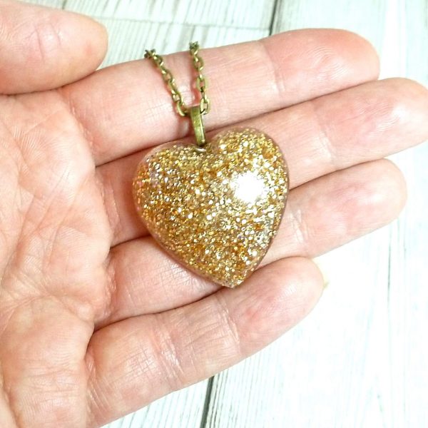 Large flake gold heart pendant on hand