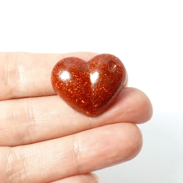 red glitter heart pin on hand