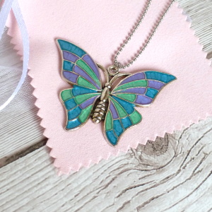 turquoise lilac green butterfly on wooden background 300px
