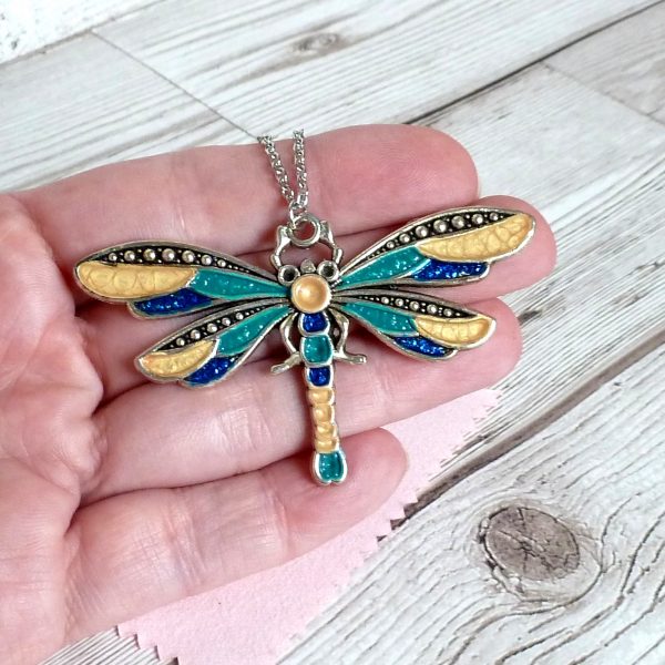 blue teal and gold dragonfly on hand