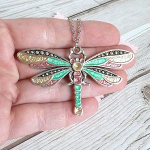 gold rose and emerald dragonfly on hand