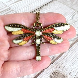 red gold white dragonfly on hand