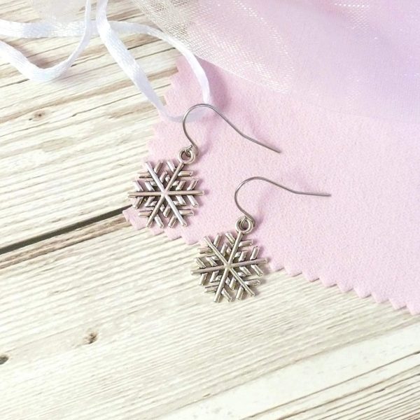 snowflake earrings on pink background